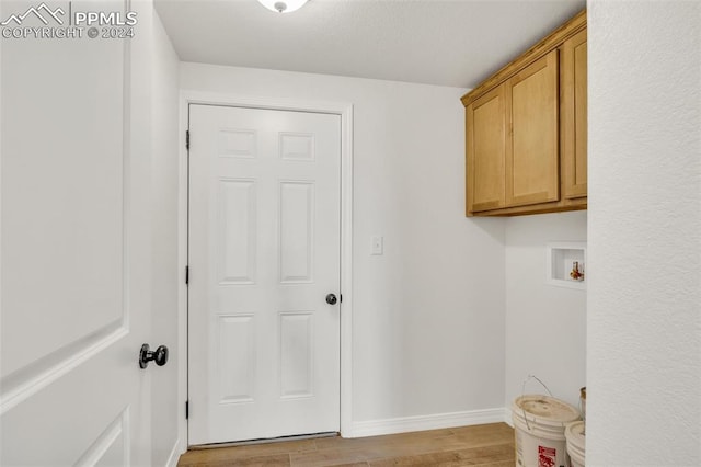 laundry area featuring hookup for a washing machine, light wood-type flooring, and cabinets