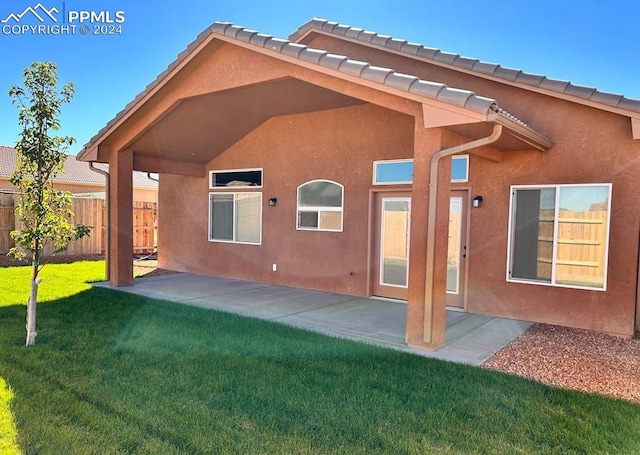 back of property with a patio area and a lawn