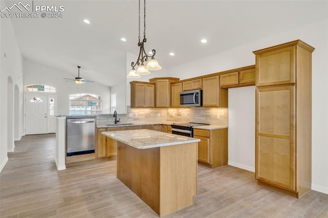 kitchen with a kitchen island, appliances with stainless steel finishes, vaulted ceiling, light hardwood / wood-style flooring, and sink