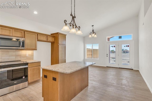 kitchen featuring light stone countertops, appliances with stainless steel finishes, a center island, hanging light fixtures, and light hardwood / wood-style floors