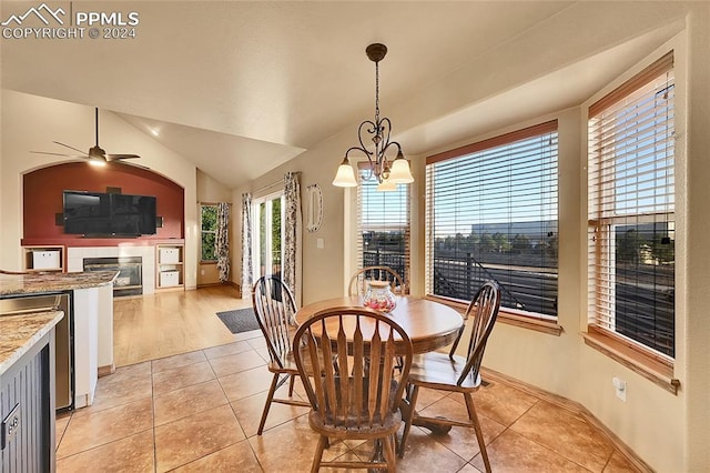 dining space with lofted ceiling, ceiling fan with notable chandelier, and light tile patterned floors