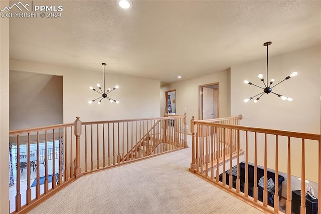 corridor featuring an inviting chandelier, a textured ceiling, and carpet flooring