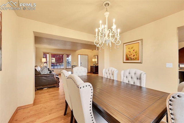 dining room with light hardwood / wood-style flooring and an inviting chandelier