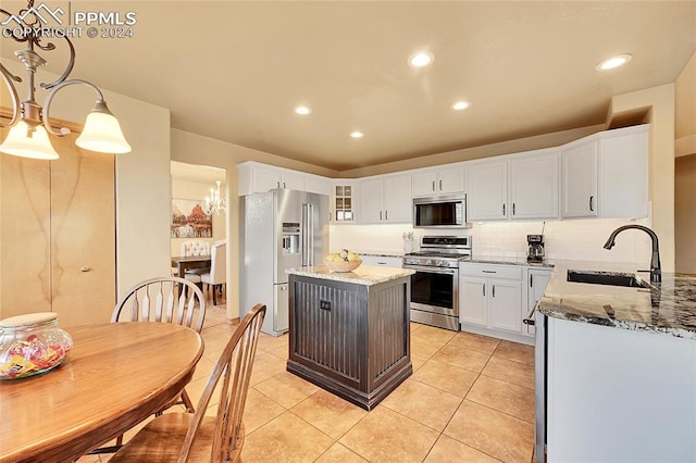 kitchen featuring a kitchen island, appliances with stainless steel finishes, white cabinetry, light stone countertops, and sink