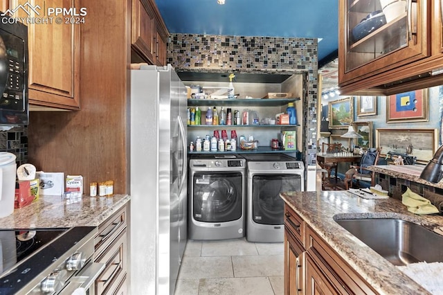 laundry area featuring washer and dryer, light tile patterned flooring, and sink