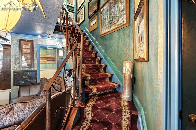 stairway with crown molding and a textured ceiling