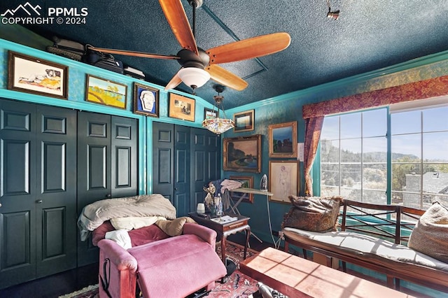 living area with ornamental molding, a textured ceiling, and ceiling fan