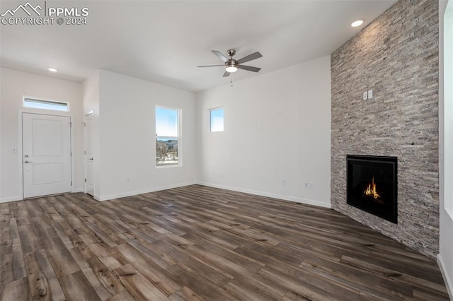 unfurnished living room with ceiling fan, a fireplace, and dark wood-type flooring