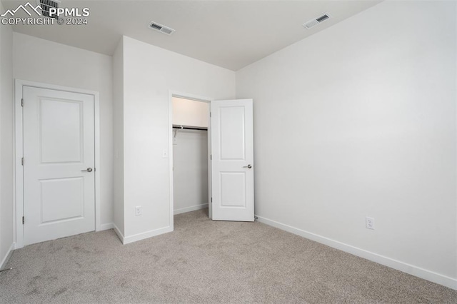 unfurnished bedroom featuring a closet and light colored carpet