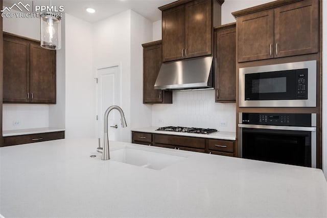 kitchen with decorative light fixtures, dark brown cabinetry, stainless steel appliances, and sink