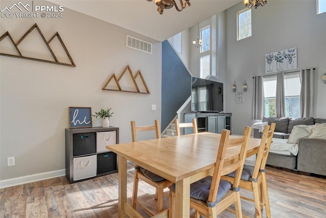 dining area featuring a towering ceiling, hardwood / wood-style flooring, and an inviting chandelier