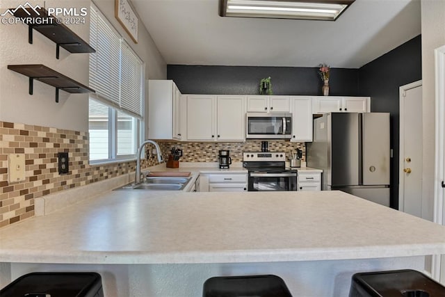 kitchen featuring sink, a kitchen breakfast bar, appliances with stainless steel finishes, and white cabinets