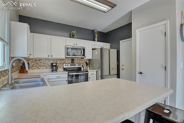 kitchen featuring sink, kitchen peninsula, stainless steel appliances, white cabinets, and a breakfast bar area