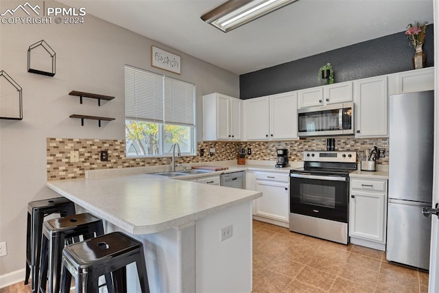 kitchen with white cabinetry, backsplash, appliances with stainless steel finishes, and kitchen peninsula