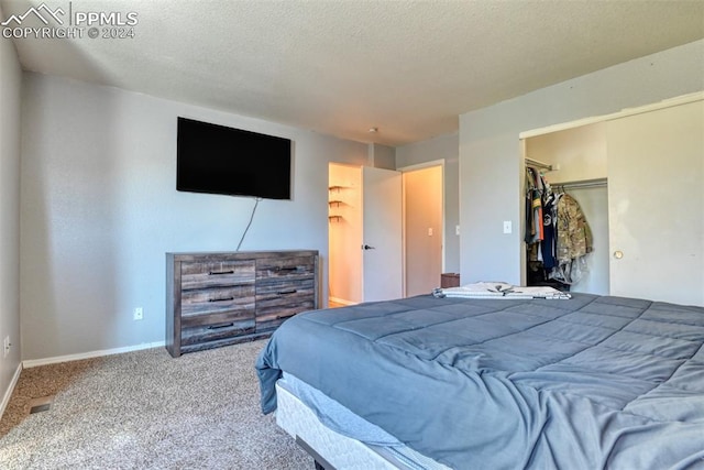 carpeted bedroom with a walk in closet, a textured ceiling, and a closet