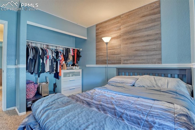 bedroom featuring wooden walls, carpet flooring, and a closet