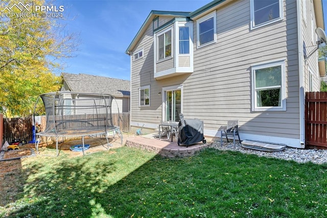 back of property with a patio, a trampoline, and a lawn