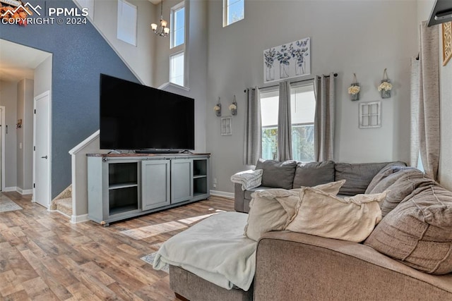 living room featuring a towering ceiling, hardwood / wood-style floors, a healthy amount of sunlight, and a chandelier