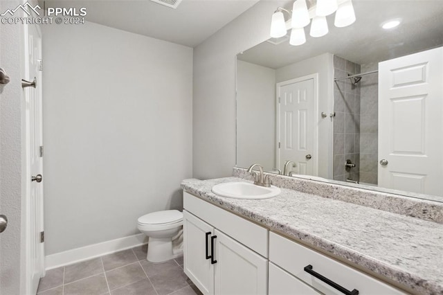 bathroom featuring vanity, a tile shower, toilet, and tile patterned floors