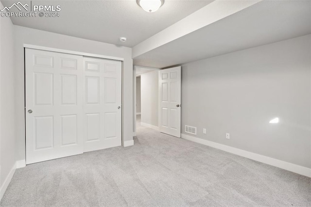 unfurnished bedroom with light carpet and a closet