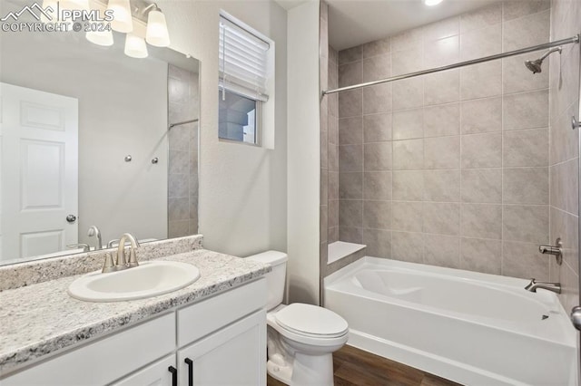 full bathroom featuring tiled shower / bath, vanity, hardwood / wood-style flooring, and toilet