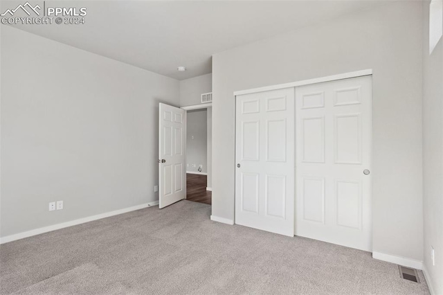 unfurnished bedroom featuring light colored carpet and a closet