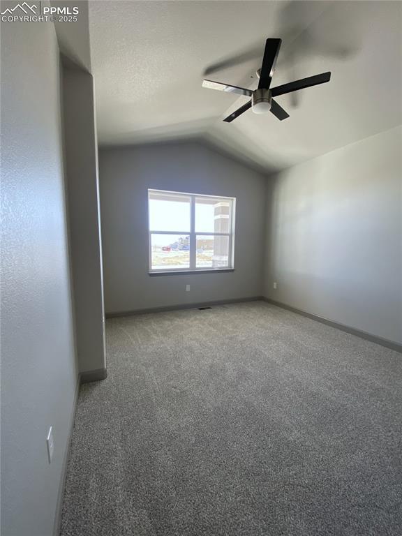 spare room with lofted ceiling, ceiling fan, carpet flooring, and baseboards