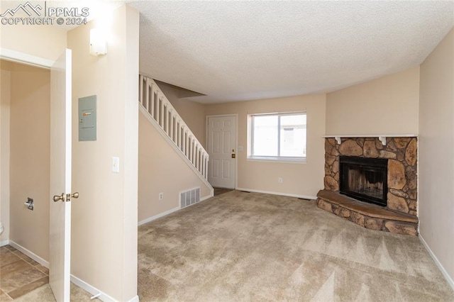 unfurnished living room with a textured ceiling, electric panel, light colored carpet, and a fireplace