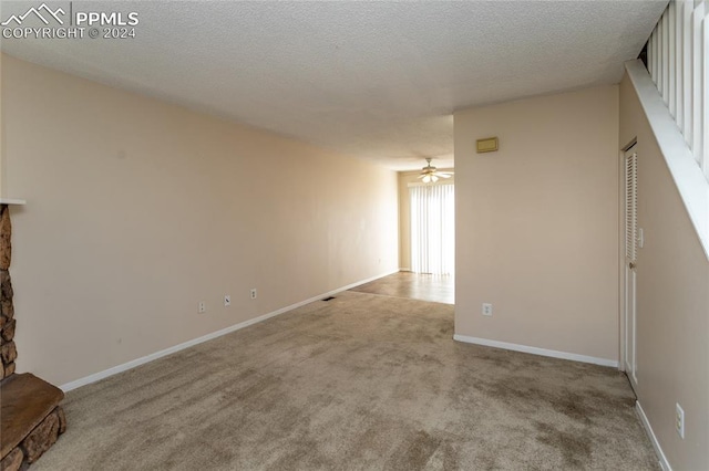 interior space with a textured ceiling, light colored carpet, and ceiling fan