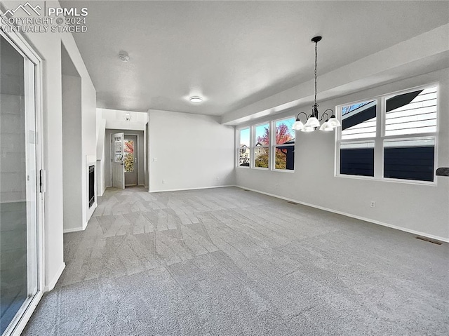 spare room with a chandelier and light colored carpet