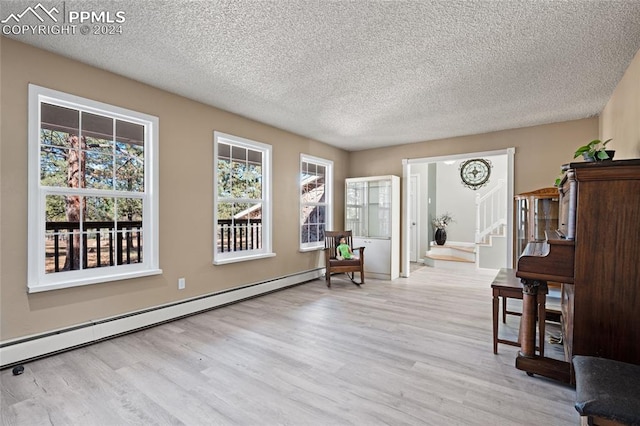 sitting room featuring a baseboard heating unit, a textured ceiling, and light wood-type flooring