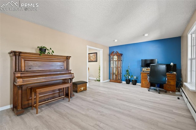 home office featuring light hardwood / wood-style flooring, a baseboard heating unit, and a textured ceiling