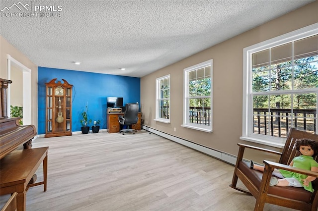 office space featuring baseboard heating, a textured ceiling, and light wood-type flooring