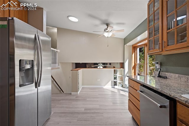 kitchen featuring stone counters, lofted ceiling, appliances with stainless steel finishes, and light wood-type flooring