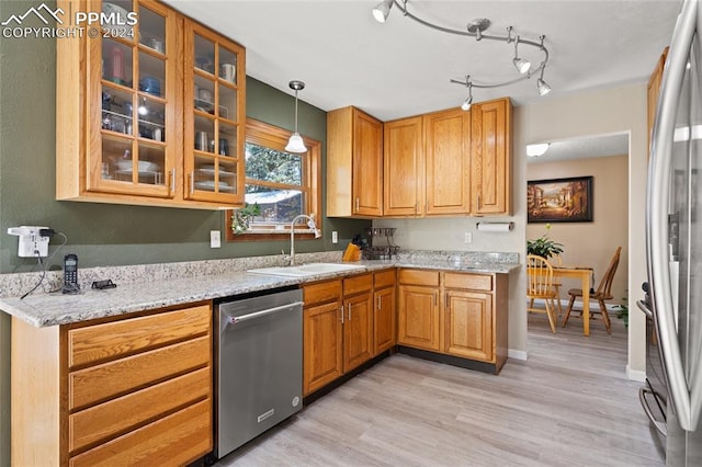 kitchen with sink, stainless steel appliances, light stone countertops, and light hardwood / wood-style flooring