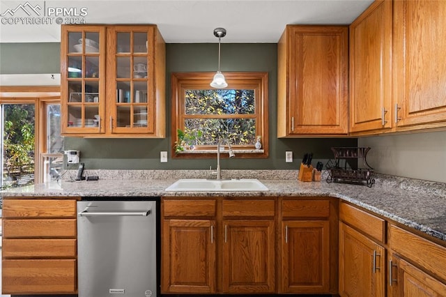 kitchen featuring dishwasher, light stone countertops, sink, and hanging light fixtures