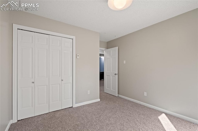 unfurnished bedroom featuring a textured ceiling, carpet floors, and a closet