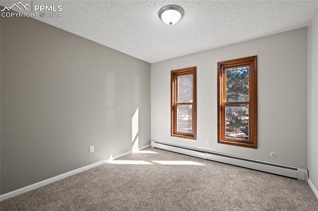 carpeted empty room featuring a baseboard heating unit and a textured ceiling