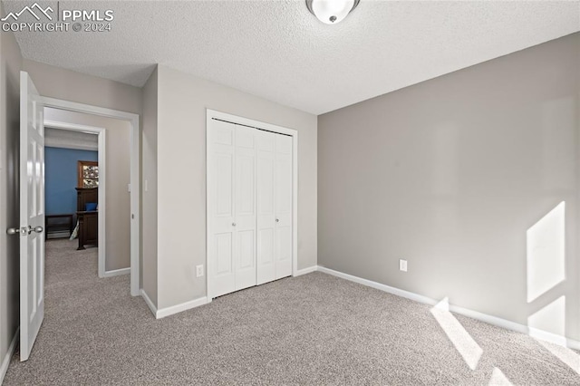 unfurnished bedroom featuring a closet, a textured ceiling, and carpet floors