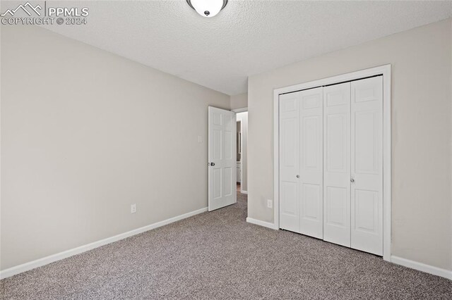 unfurnished bedroom with a closet, a textured ceiling, and carpet