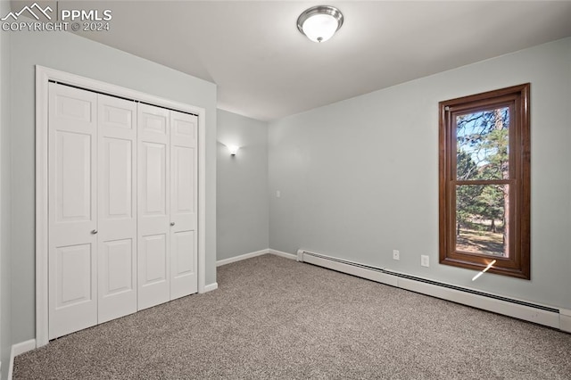 unfurnished bedroom with baseboard heating, carpet floors, and a closet