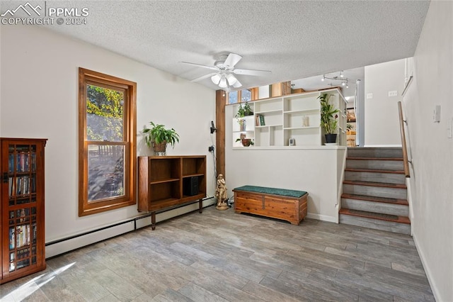 interior space with ceiling fan, hardwood / wood-style flooring, a textured ceiling, and a baseboard heating unit