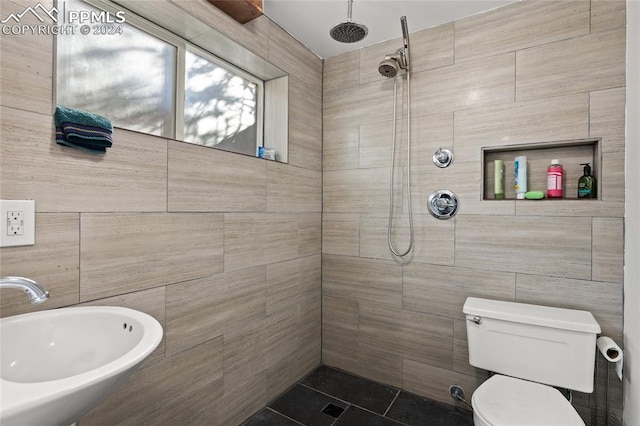 bathroom with tiled shower, tile patterned floors, toilet, sink, and tile walls