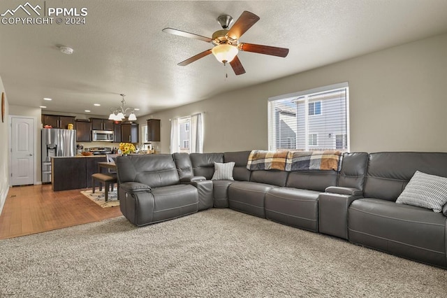 living room with hardwood / wood-style floors, a textured ceiling, and ceiling fan with notable chandelier