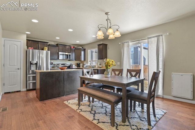 dining space featuring wood-type flooring and an inviting chandelier