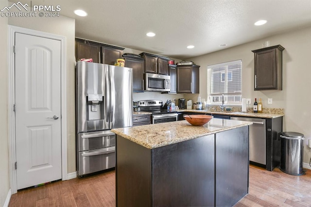 kitchen featuring light hardwood / wood-style floors, stainless steel appliances, dark brown cabinetry, and a center island