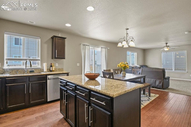 kitchen with pendant lighting, stainless steel dishwasher, light wood-type flooring, and a kitchen island