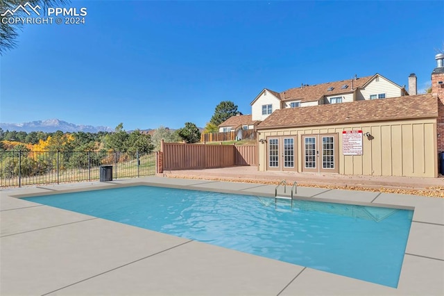 view of pool featuring a mountain view, an outdoor structure, and a patio