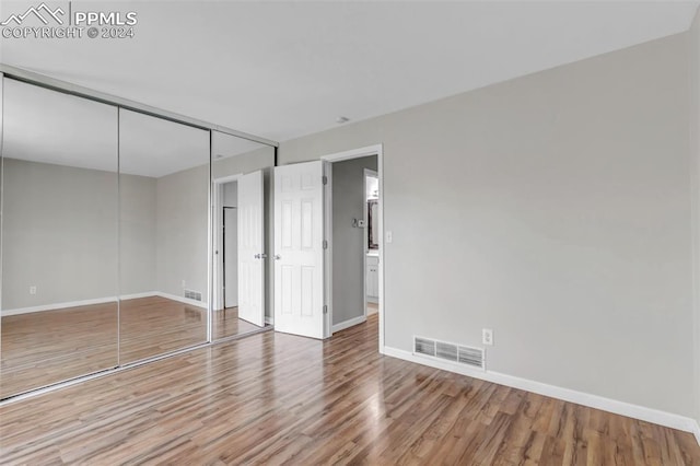 unfurnished bedroom featuring a closet and hardwood / wood-style flooring