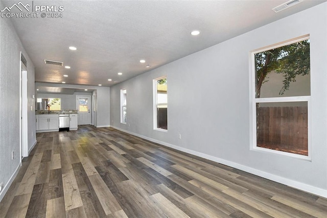 unfurnished living room with dark wood-type flooring and a textured ceiling